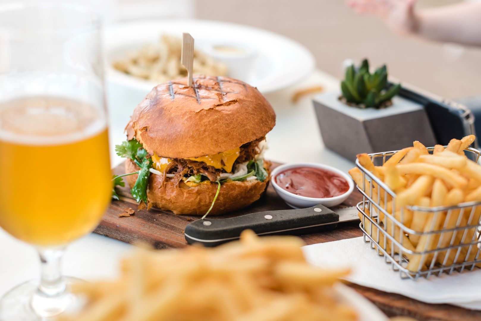 a burger, fries, and a beer on a restaurant table. 