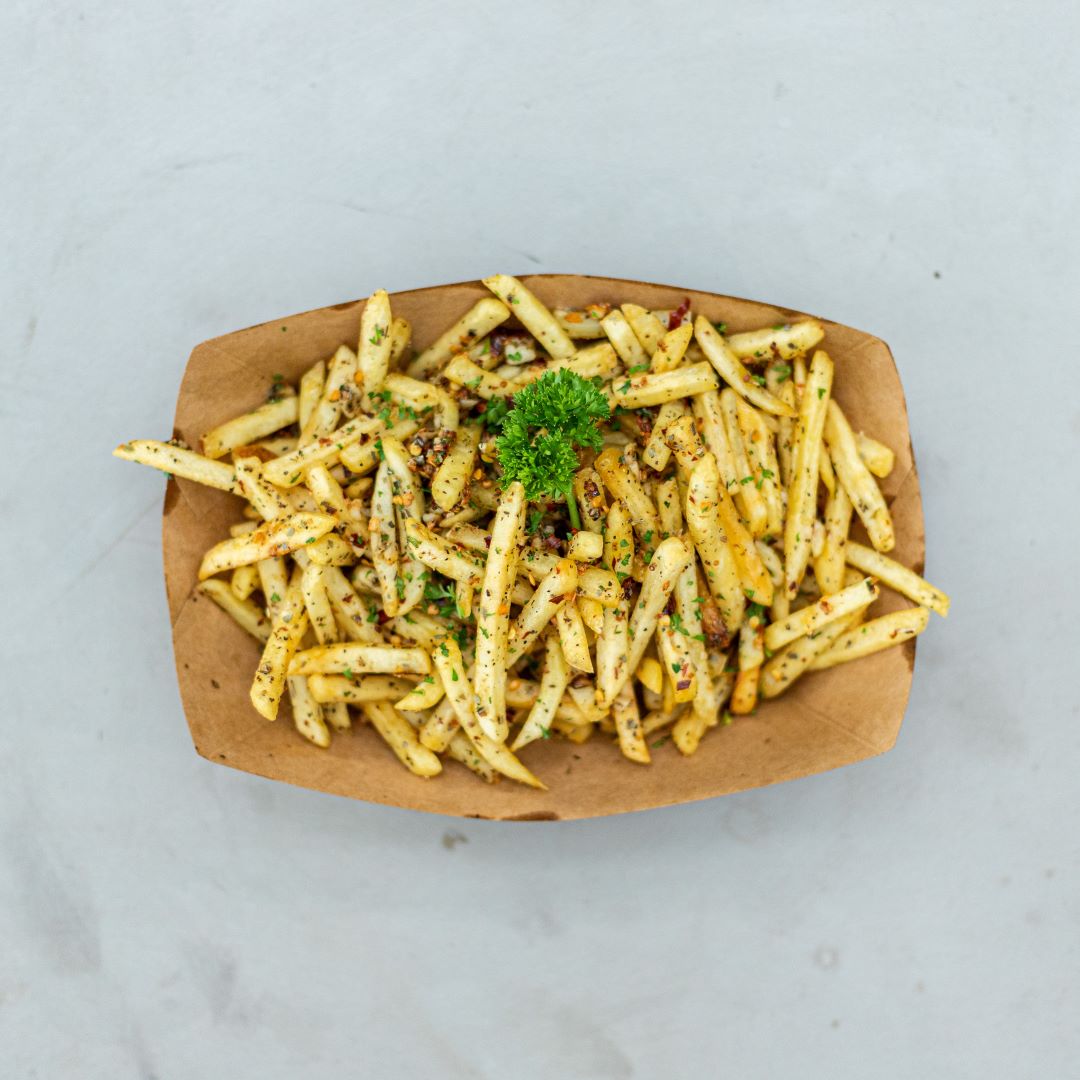 french fries seasoned with garlic and spices in a brown craft paper container. 